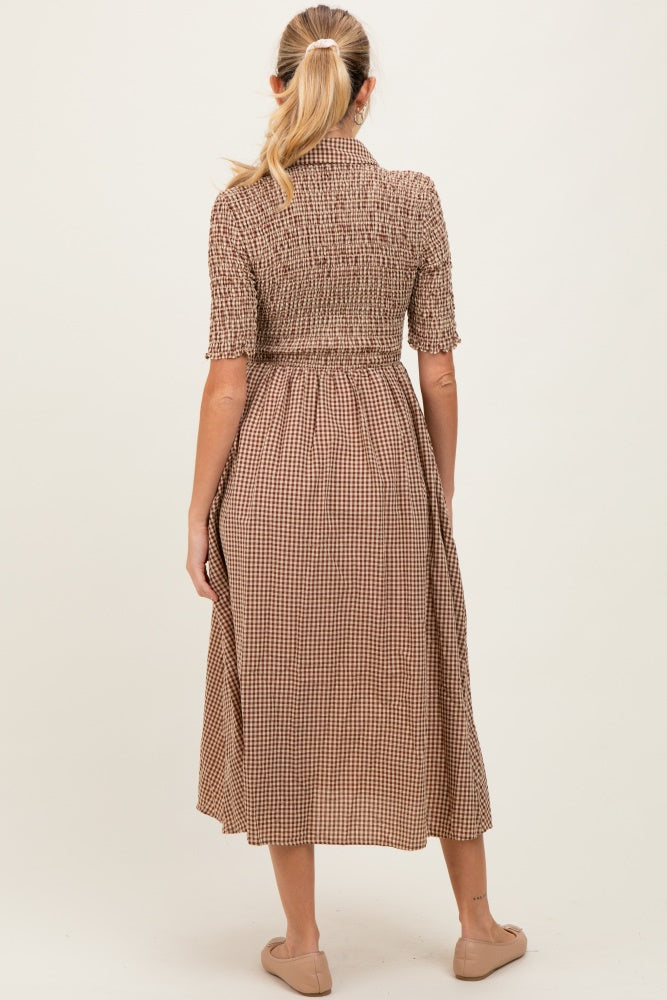 woman wearing a brown and cream checkered maternity dress with a smocked bodice and mid-calf length