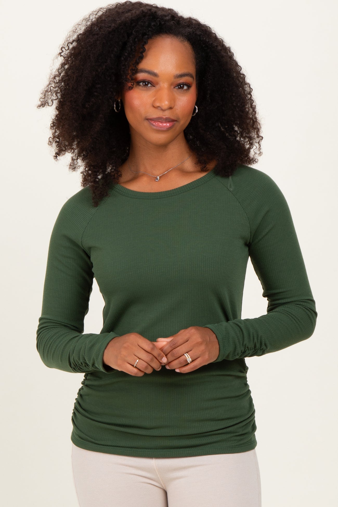 woman wearing a dark green long sleeve ribbed top with a relaxed fit and gathered side detail