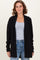 woman wearing a black ribbed open-front cardigan over a gray t-shirt and blue jeans