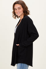 woman wearing a black long sleeve open front cardigan with pockets and paired with a gray top and blue jeans