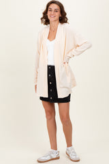 woman wearing a light peach ribbed cardigan over a white top and black button-up skirt with white sneakers