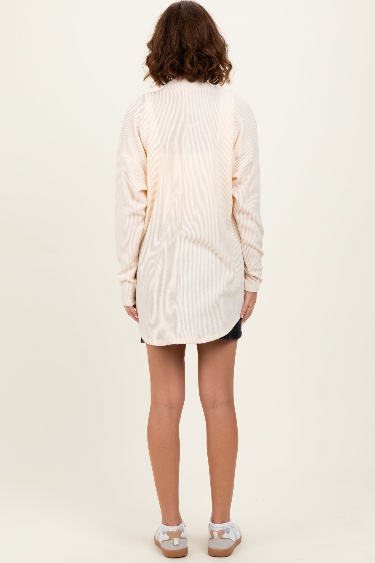 woman wearing a light cream long sleeve ribbed tunic with a relaxed fit, shown from the back