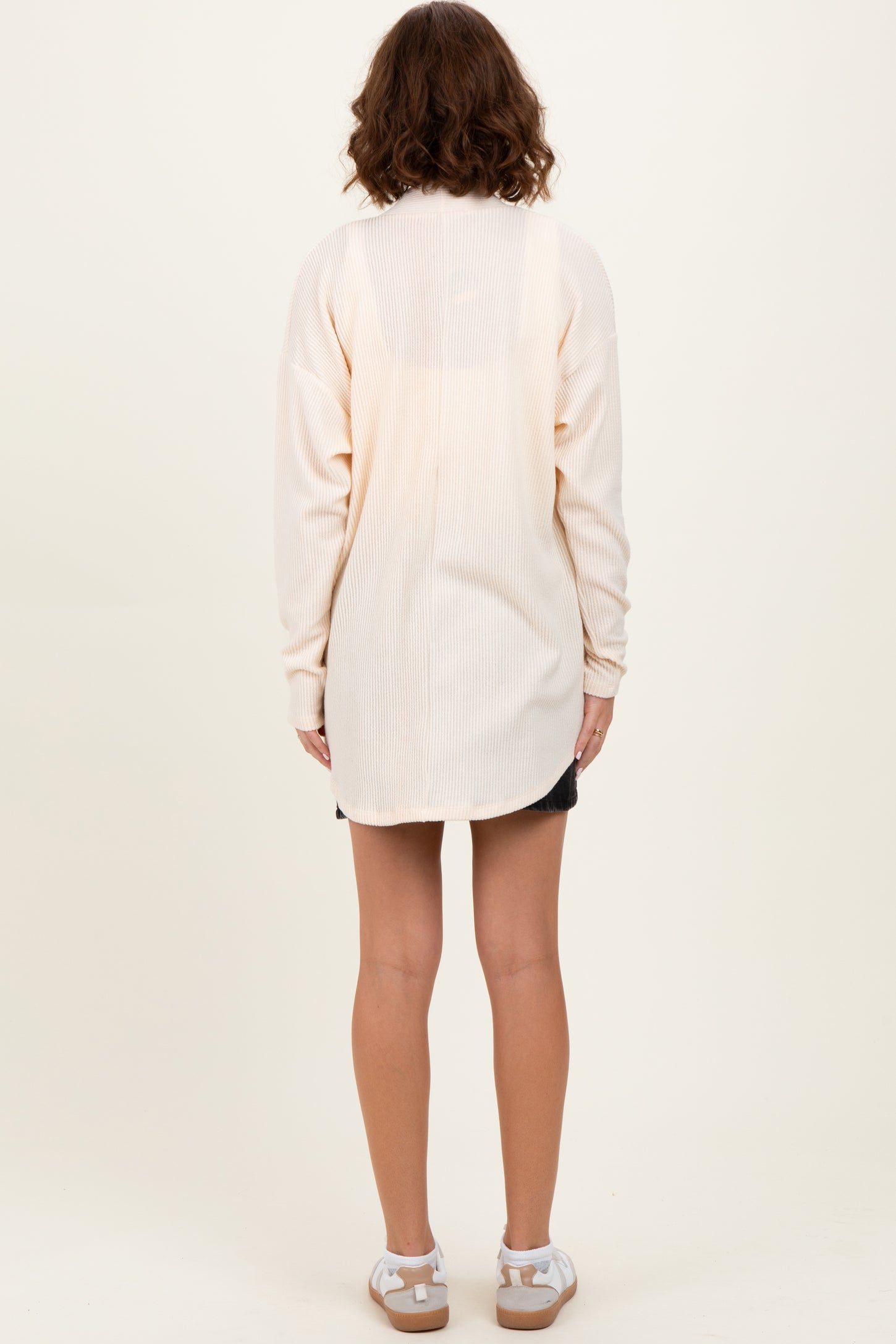 woman wearing a light cream long sleeve ribbed tunic with a relaxed fit, shown from the back