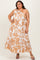 woman wearing a white and orange floral one-shoulder maxi dress with a ruffled hem and a confident pose