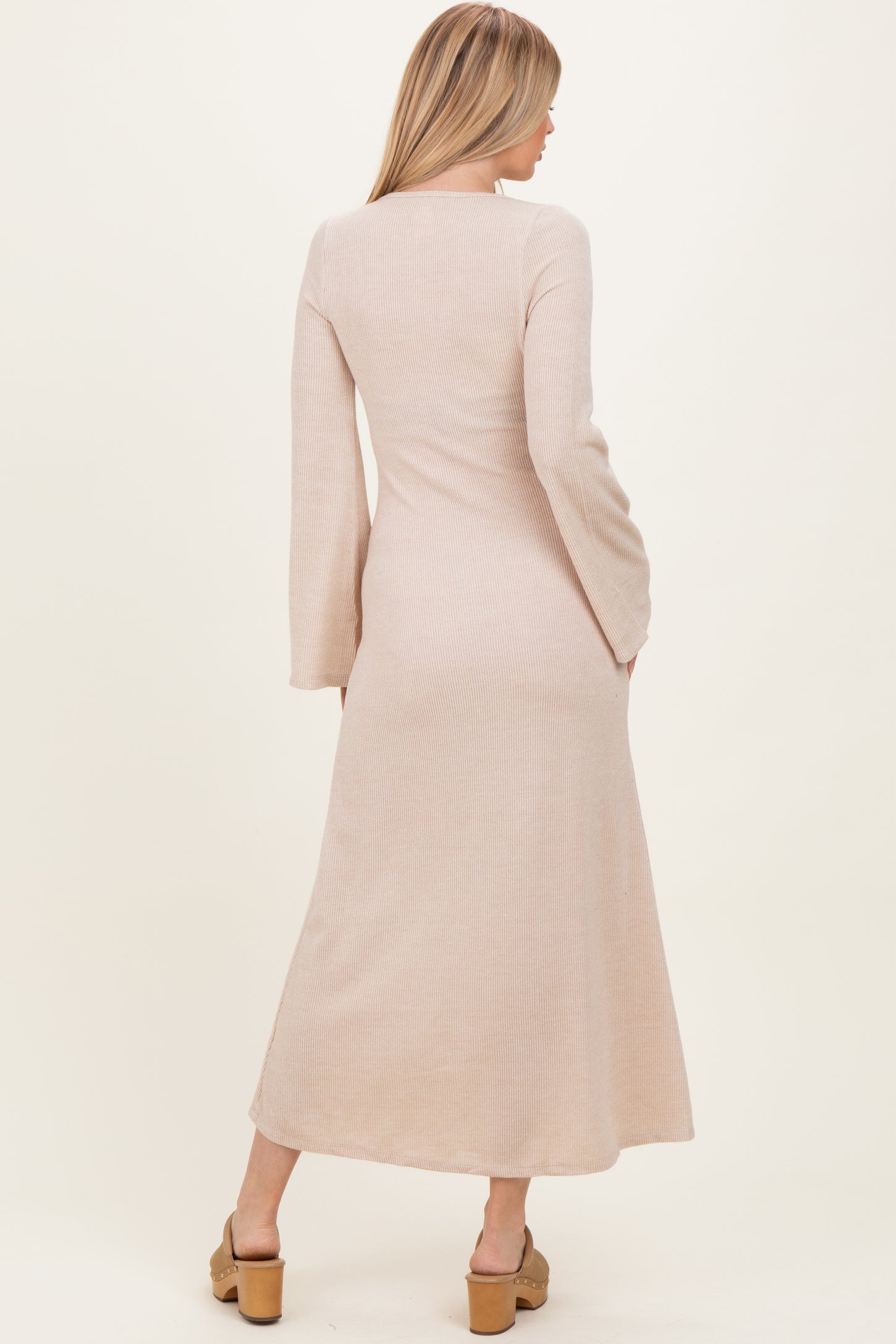 woman wearing a long sleeve beige ribbed maxi dress, viewed from the back