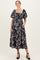 woman wearing a black floral maternity dress with puff sleeves and pockets, displaying her baby bump