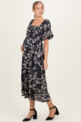 woman wearing a black floral maternity dress with puff sleeves and a baby bump visible