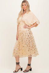 woman wearing a beige midi dress with floral embroidery and short sleeves, standing in stylish black heeled sandals