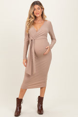 woman wearing a taupe long sleeve maternity dress with a wrap tie detail and a visible baby bump