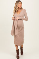 woman wearing a beige long sleeve maternity dress with a tie detail and a visible baby bump