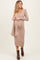 woman wearing a beige long sleeve maternity dress with a tie detail and a visible baby bump
