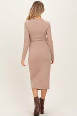 woman wearing a long sleeve taupe ribbed maternity dress with a fitted silhouette and mid-calf length