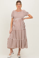 woman wearing a brown and white striped maternity maxi dress with short sleeves and a tiered skirt, showing her baby bump
