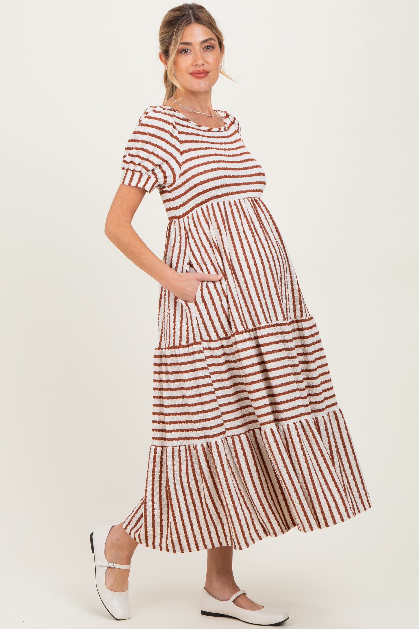 woman wearing a striped maternity maxi dress with short sleeves and pockets, showcasing a baby bump