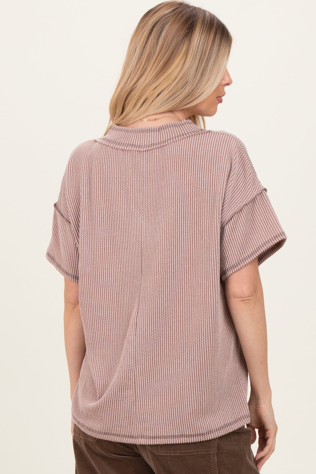 woman wearing a mauve short sleeve oversized ribbed top with a relaxed fit and a round neckline