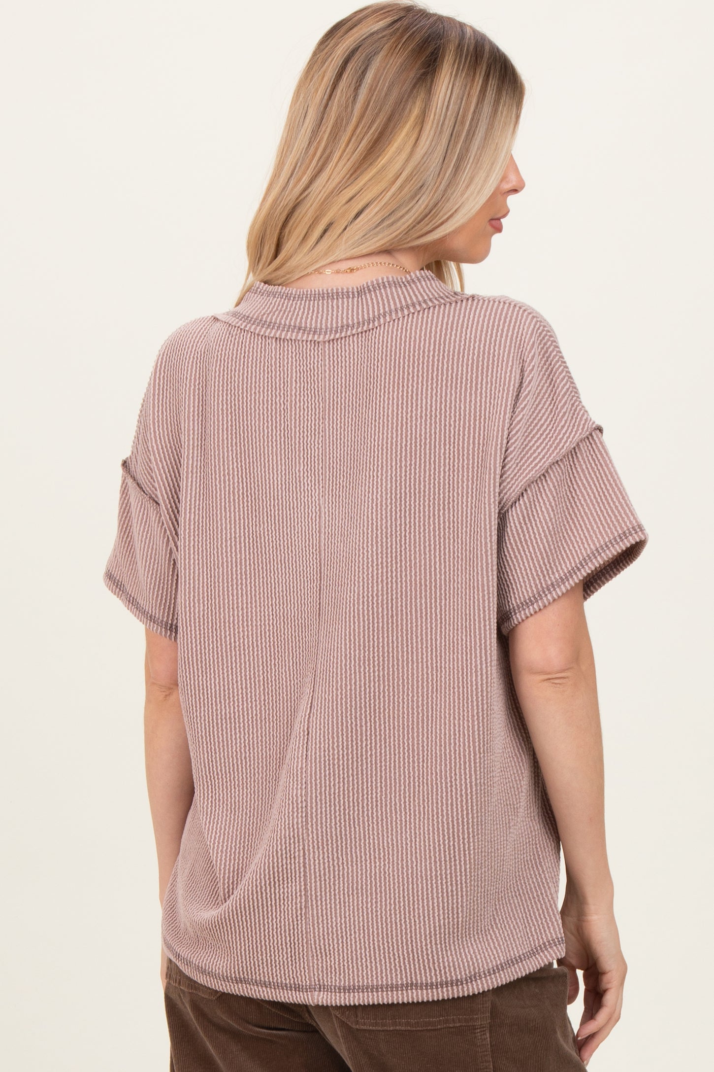 woman wearing a mauve short sleeve oversized ribbed top with a relaxed fit and a round neckline
