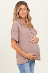woman wearing a mauve striped maternity top and holding her baby bump