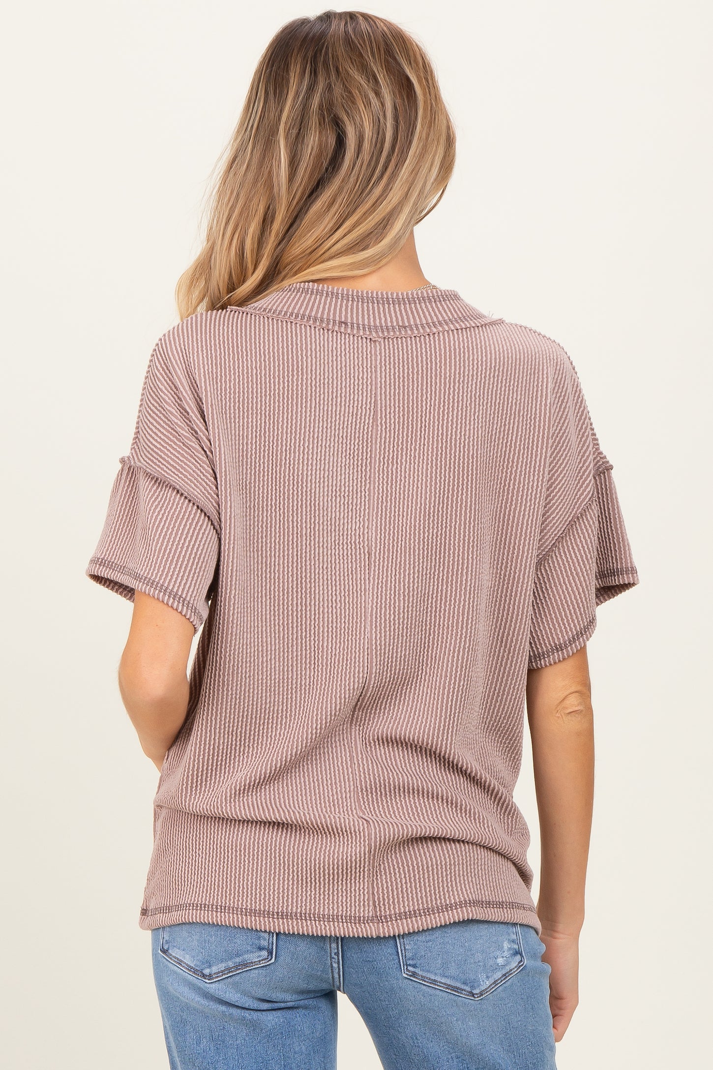woman wearing a light brown short sleeve maternity top with ribbed texture and relaxed fit seen from the back