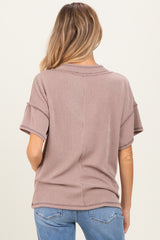 woman wearing a light brown short sleeve maternity top with ribbed texture and relaxed fit seen from the back