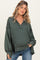 woman wearing a dark green maternity pullover with a v-neck and loose sleeves, styled with casual blue jeans