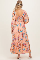 woman wearing a peach floral maternity maxi dress with puff sleeves and a smocked bodice, showing a baby bump from the back