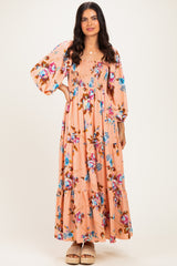 woman wearing a pink floral maxi dress with puff sleeves and tiered hem, standing against a neutral background