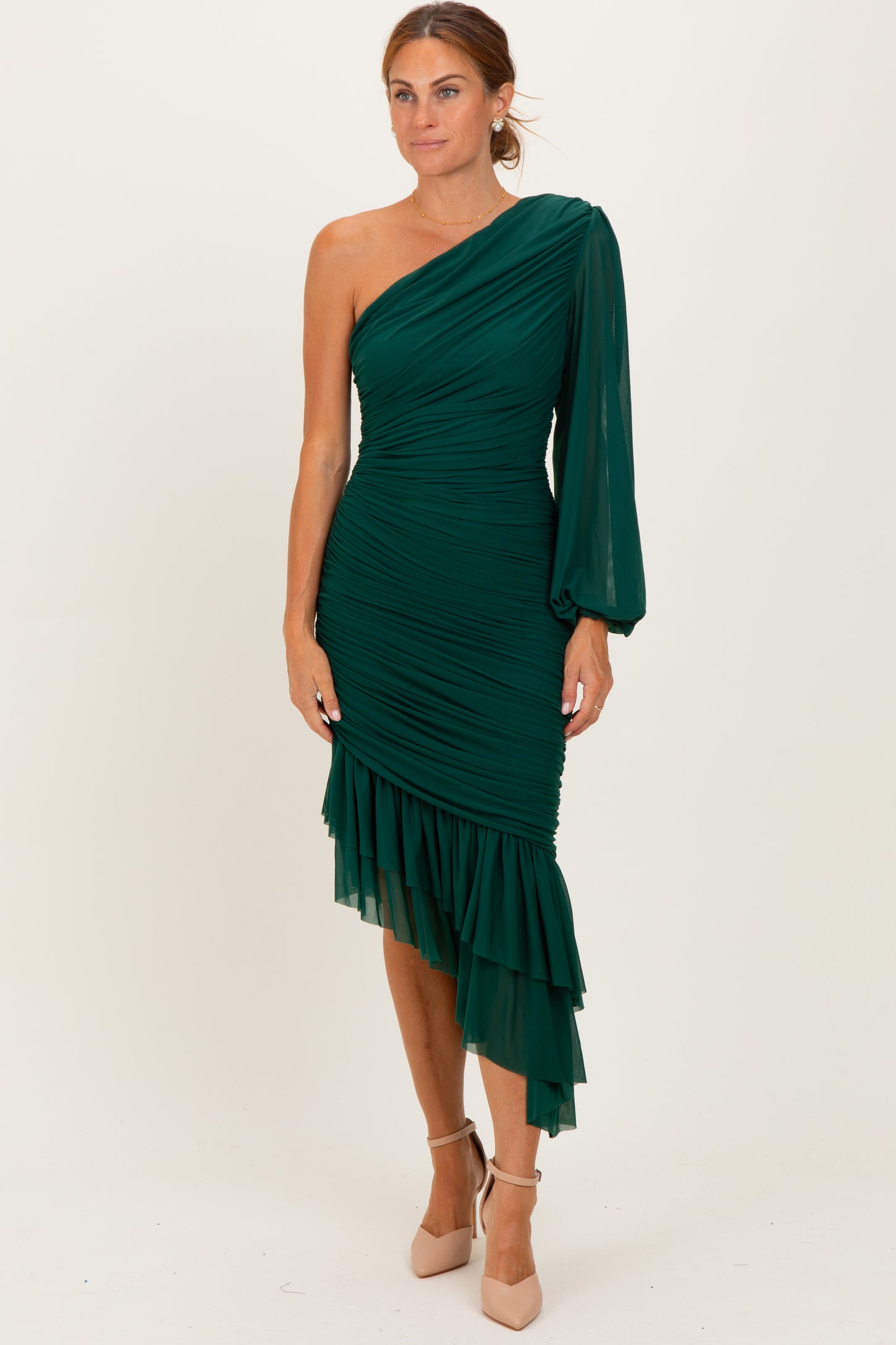 woman wearing a green one-shoulder ruched dress with ruffled hem and long sleeve detail