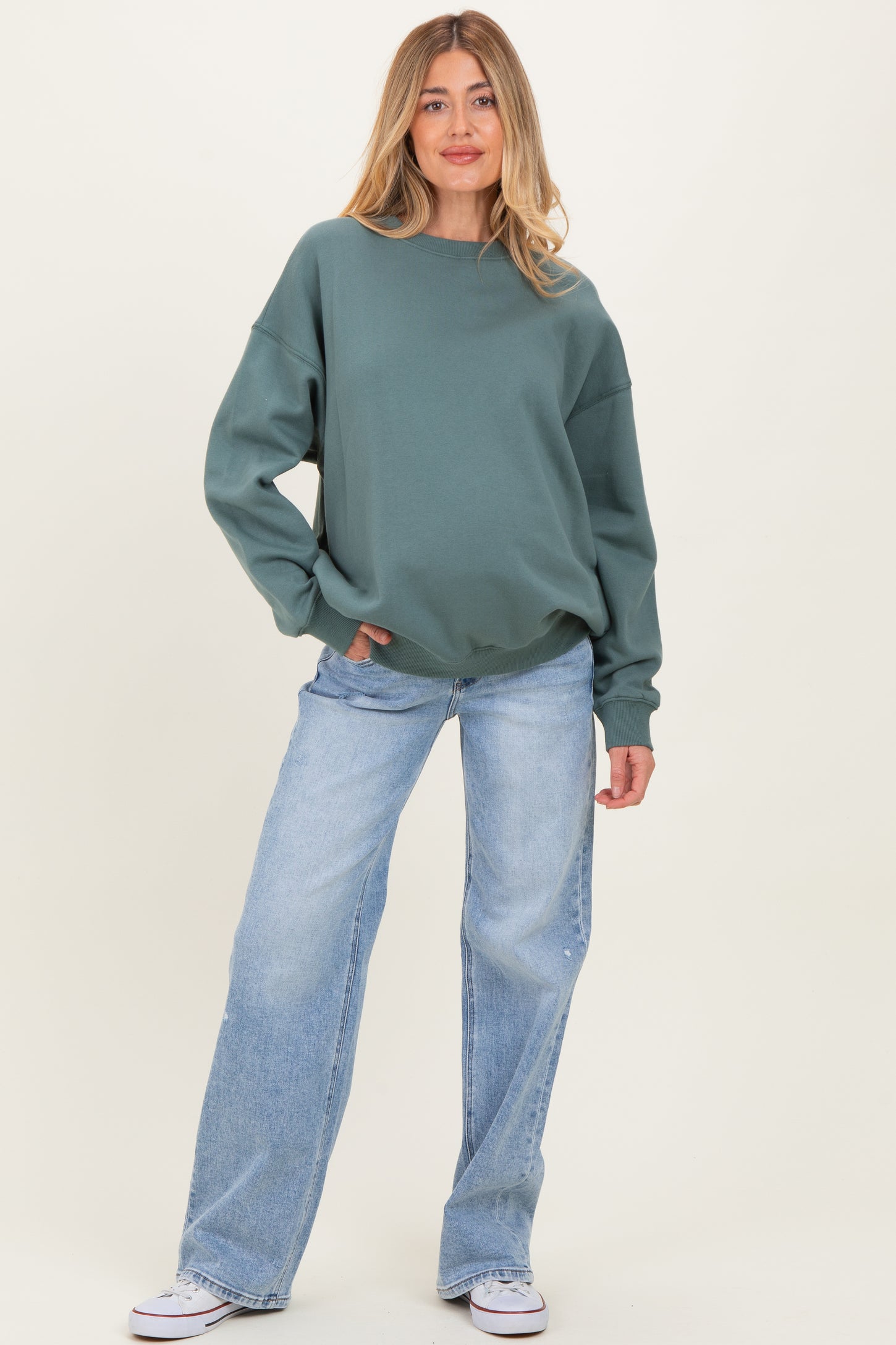 woman wearing a green oversized sweatshirt with long sleeves and light blue wide-leg jeans