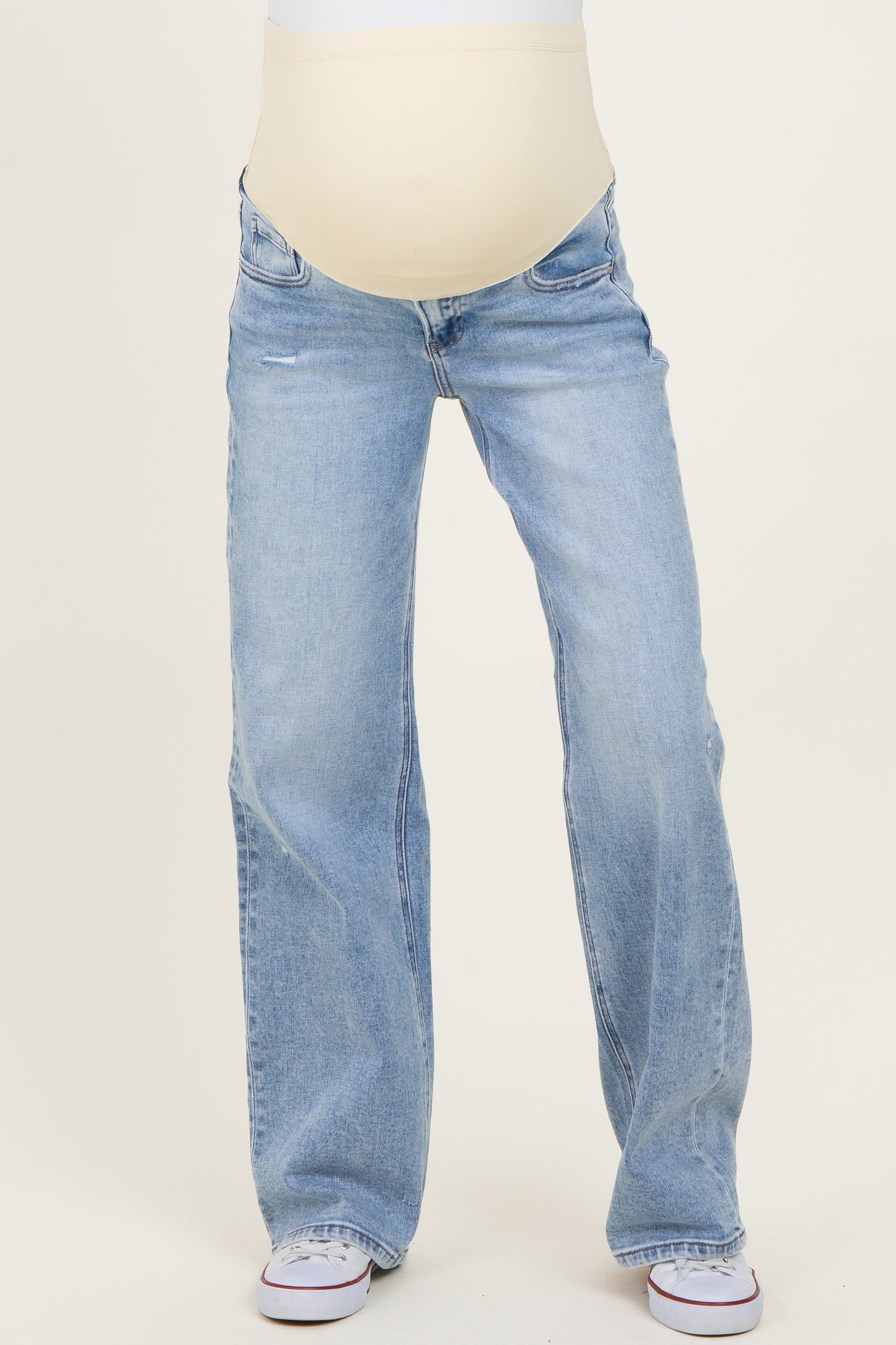woman wearing light blue maternity jeans with a stretchy beige panel for belly support