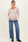 woman wearing a beige ribbed long sleeve maternity top with a baby bump and blue wide-leg jeans