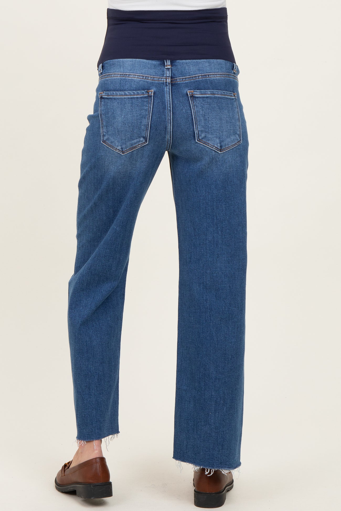 woman wearing blue maternity jeans with a fitted waistband and frayed hem, seen from the back