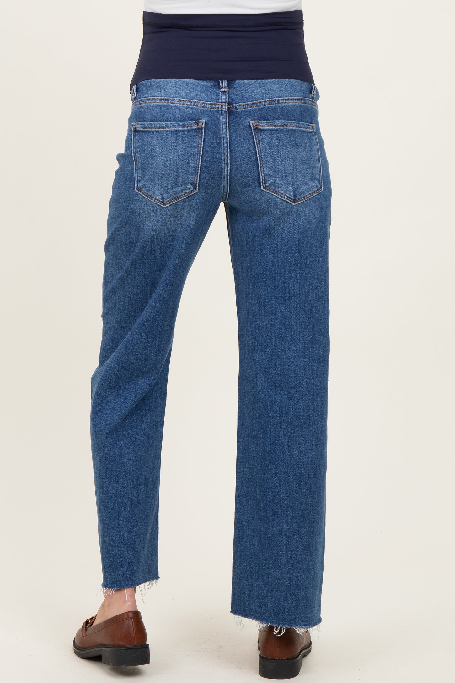woman wearing blue maternity jeans with a fitted waistband and frayed hem, seen from the back