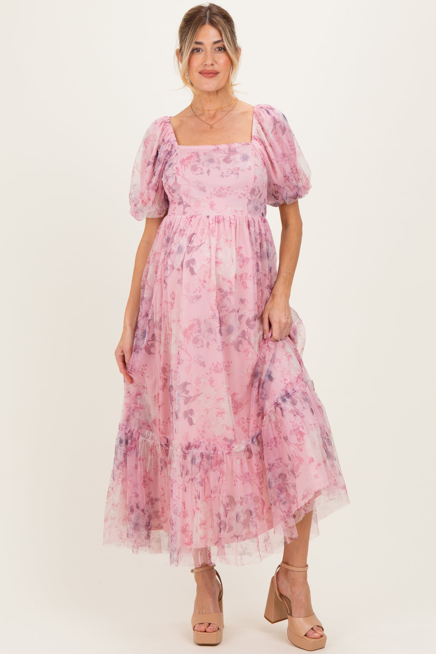 woman wearing a pink floral maternity dress with puff sleeves and a tiered skirt