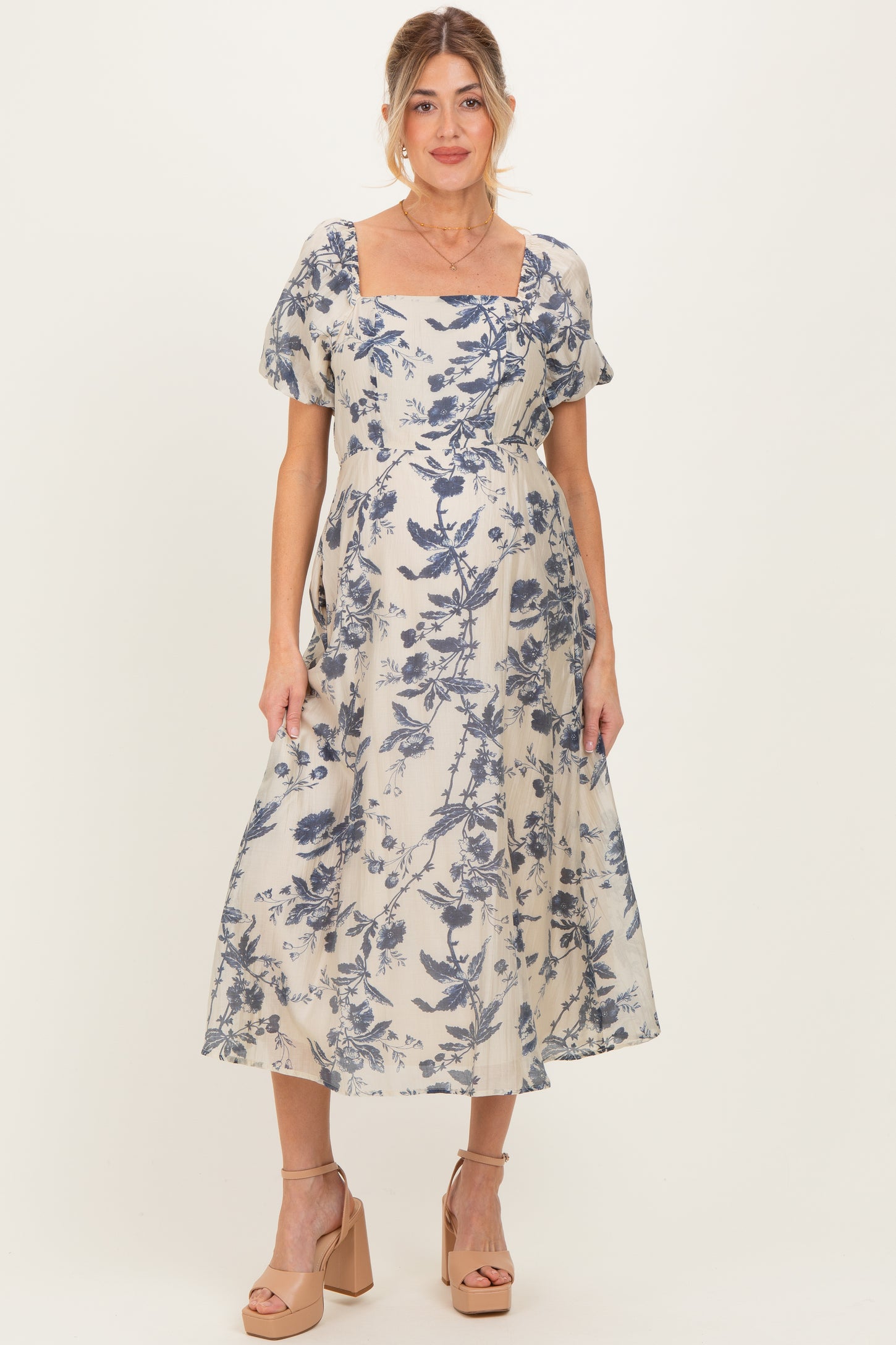 woman wearing a floral print maternity dress with short sleeves and a square neckline, showcasing her baby bump