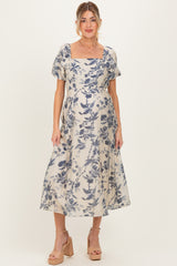 woman wearing a floral print maternity dress with short sleeves and a square neckline, showcasing her baby bump