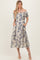 woman wearing a floral off-the-shoulder midi dress with pockets and a light beige background