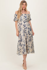 woman wearing a cream off-the-shoulder floral midi dress with puff sleeves and a flowing skirt