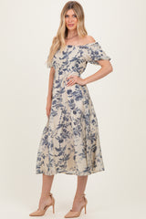 woman wearing a floral off-the-shoulder midi dress in beige and blue with short puff sleeves and a fitted waist