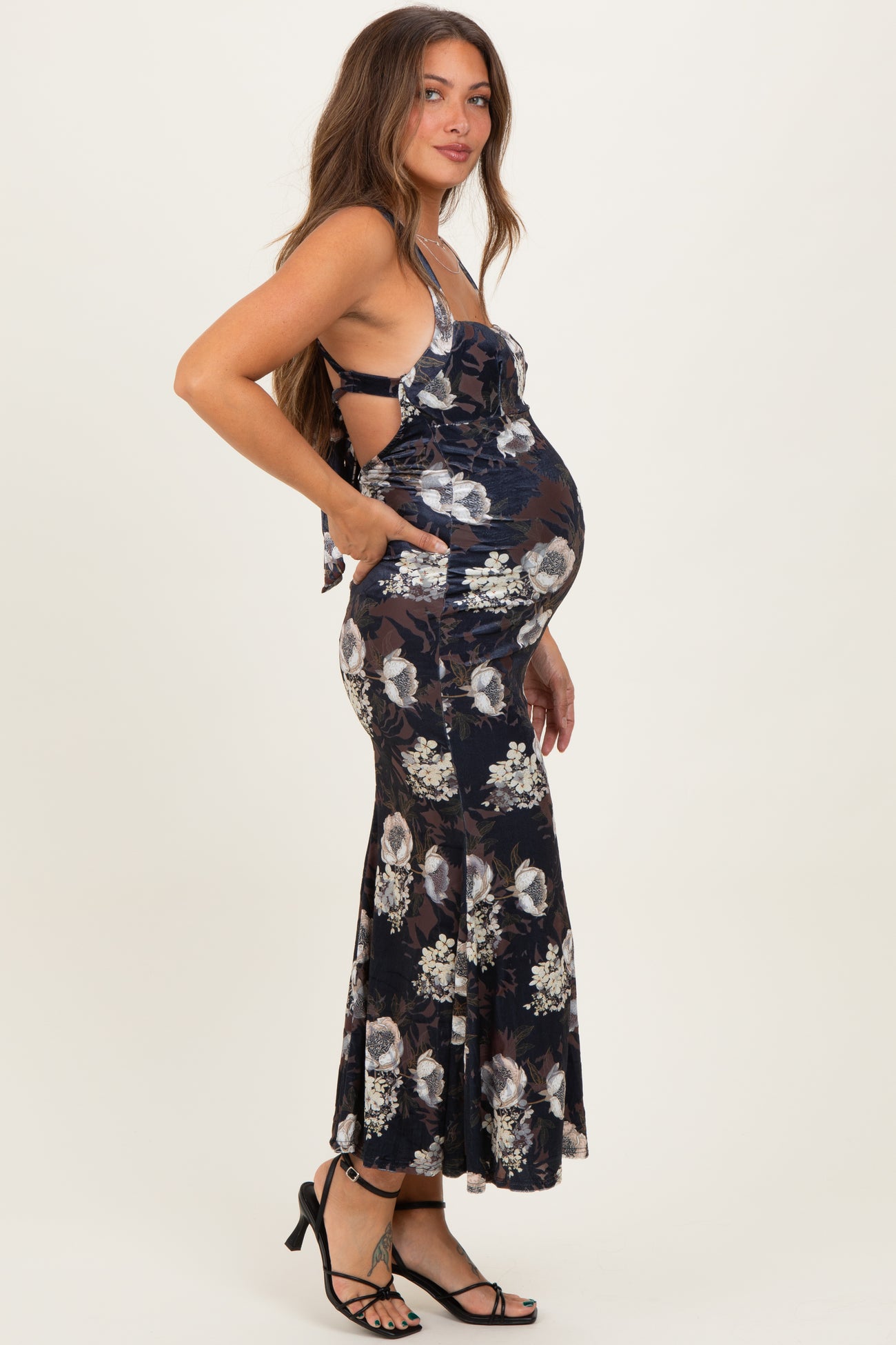 woman wearing a navy floral print maternity dress with a fitted bodice and flared skirt, showing her baby bump
