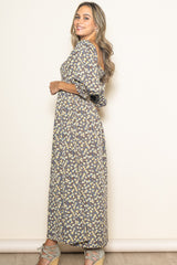 woman wearing a long floral maxi dress with puff sleeves and a tiered skirt, standing sideways against a plain background