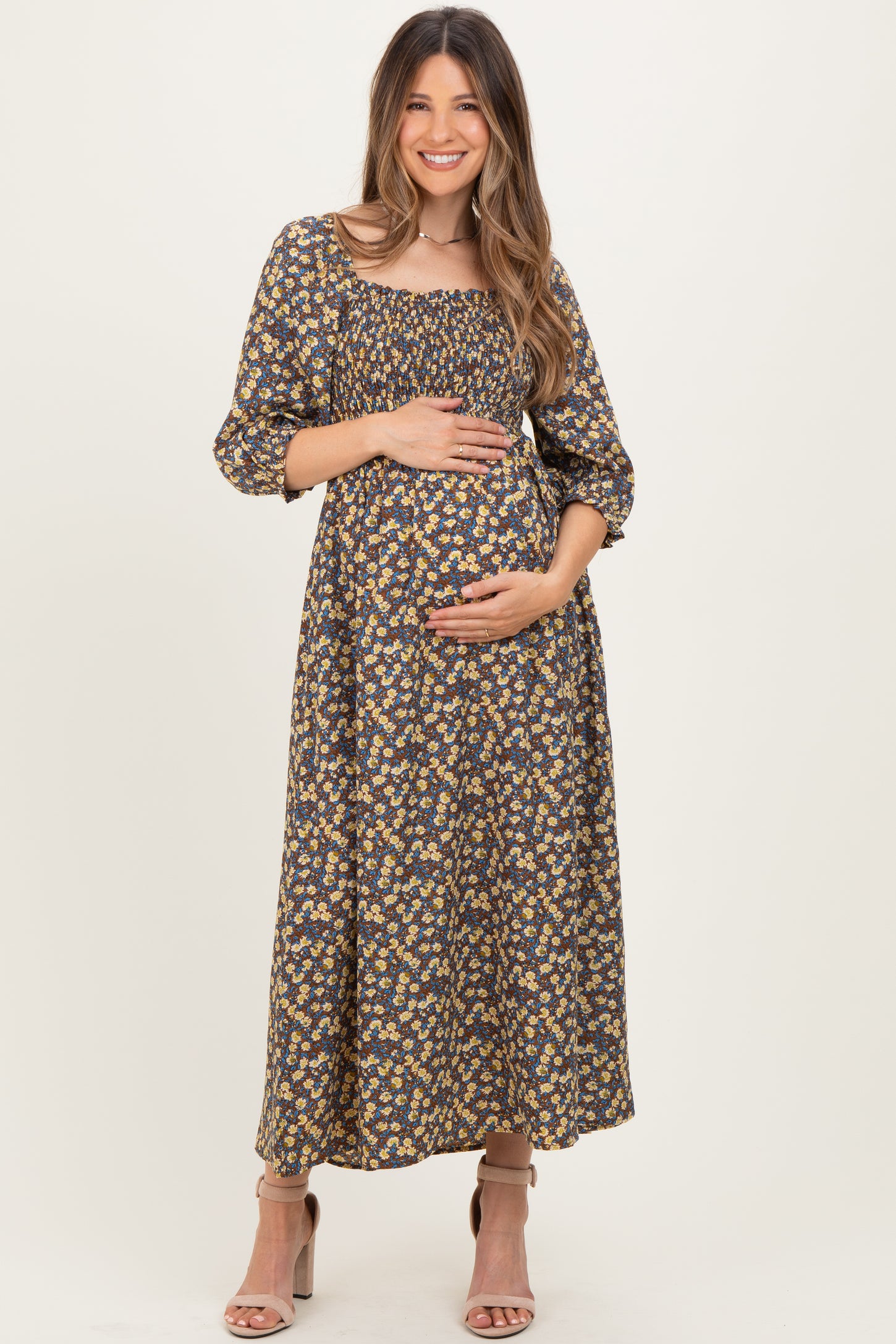 woman wearing a dark floral maternity maxi dress and holding her baby bump