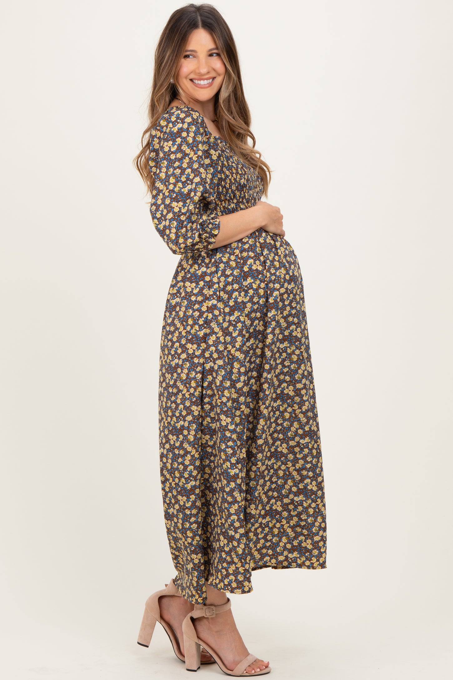 woman wearing a navy blue floral maternity maxi dress, showing her baby bump and styled with heeled sandals