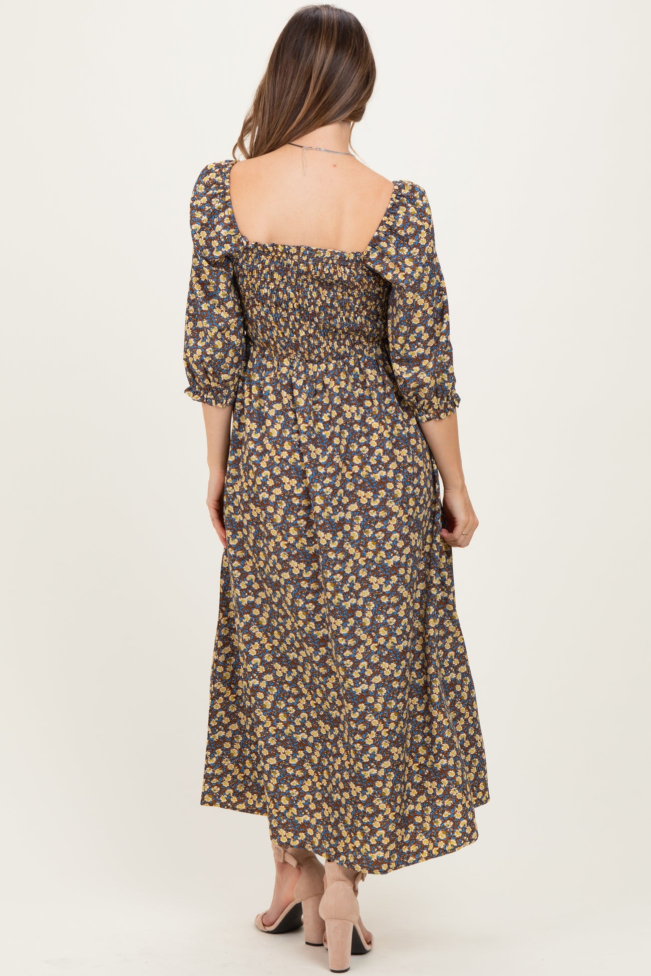 woman wearing a floral maternity maxi dress with smocked details and puff sleeves, showing a baby bump