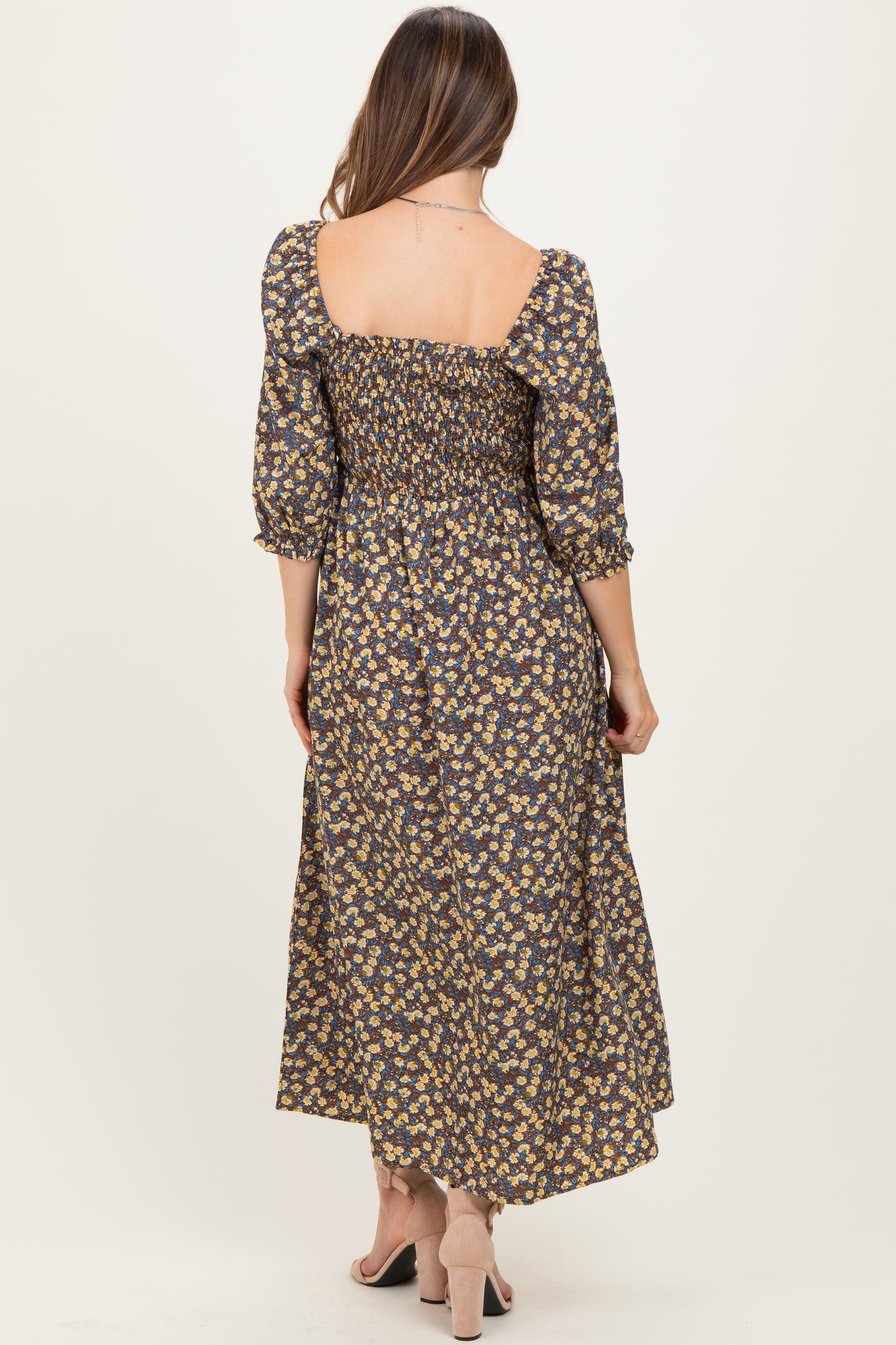 woman wearing a floral maternity maxi dress with smocked details and puff sleeves, showing a baby bump