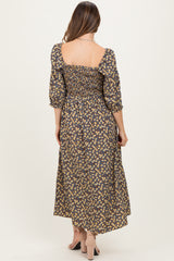 woman wearing a floral maternity maxi dress with smocked details and puff sleeves, showing a baby bump