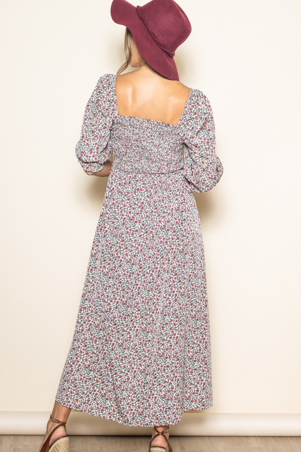 woman wearing a floral maxi dress with puff sleeves and a square back, paired with a wide-brimmed hat