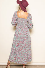woman wearing a floral maxi dress with puff sleeves and a square back, paired with a wide-brimmed hat