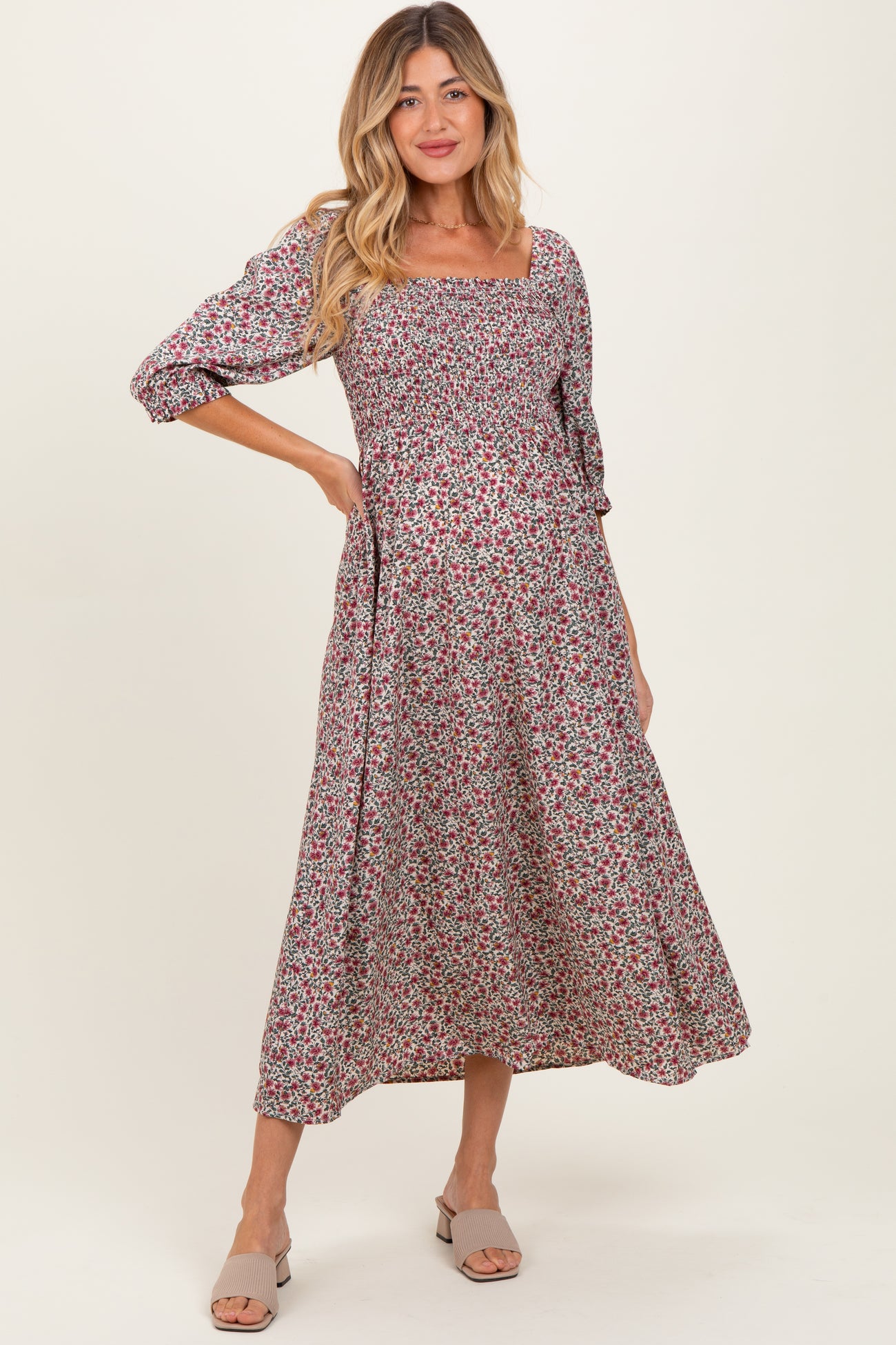 woman wearing a floral print maternity dress with a square neckline and three-quarter length sleeves, showing her baby bump