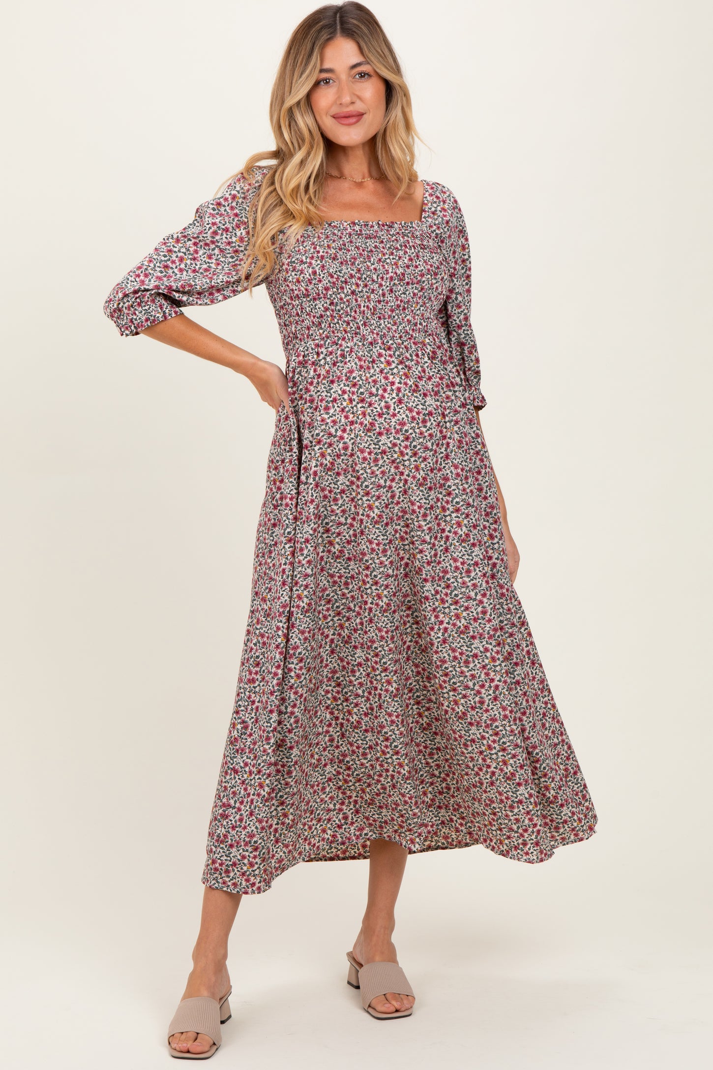 woman wearing a floral print maternity dress with a square neckline and three-quarter length sleeves, showing her baby bump