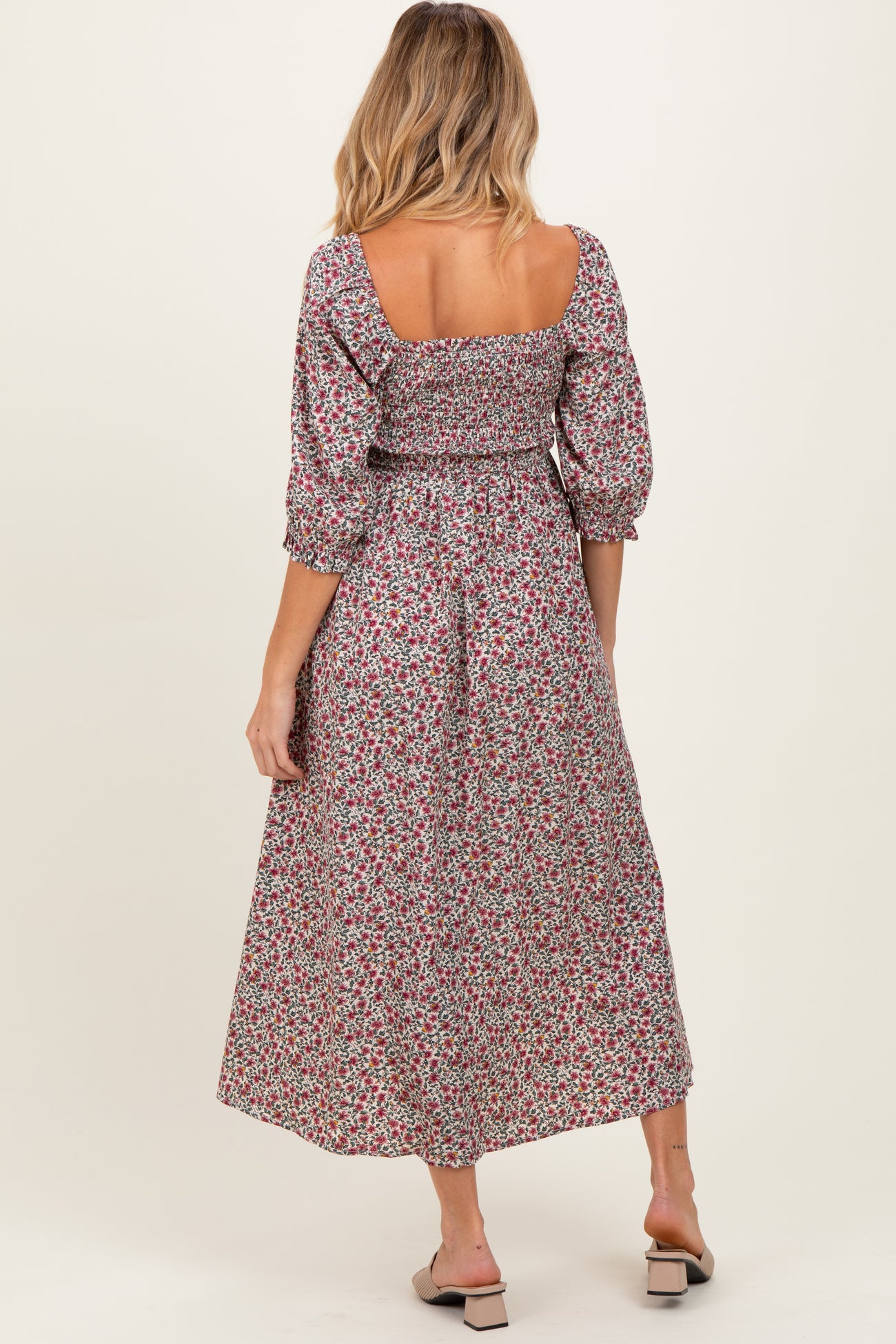woman wearing a floral maternity dress with puff sleeves and a cinched waist, showing a baby bump from the back